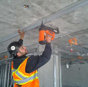 Workman attaches metal frame to concrete ceiling
