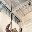 Man uses pole to reach high ceiling without a ladder