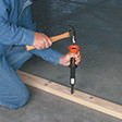 Workman uses hammer and Hammershot to attach wooden 2x4 to concrete floor